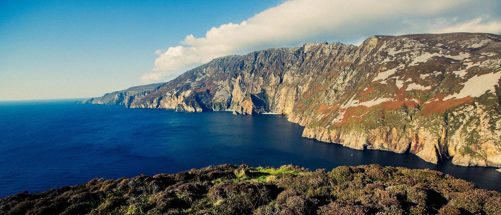 The great cliffs of Sliabh Liag rise above a deep blue Atlantic Ocean.