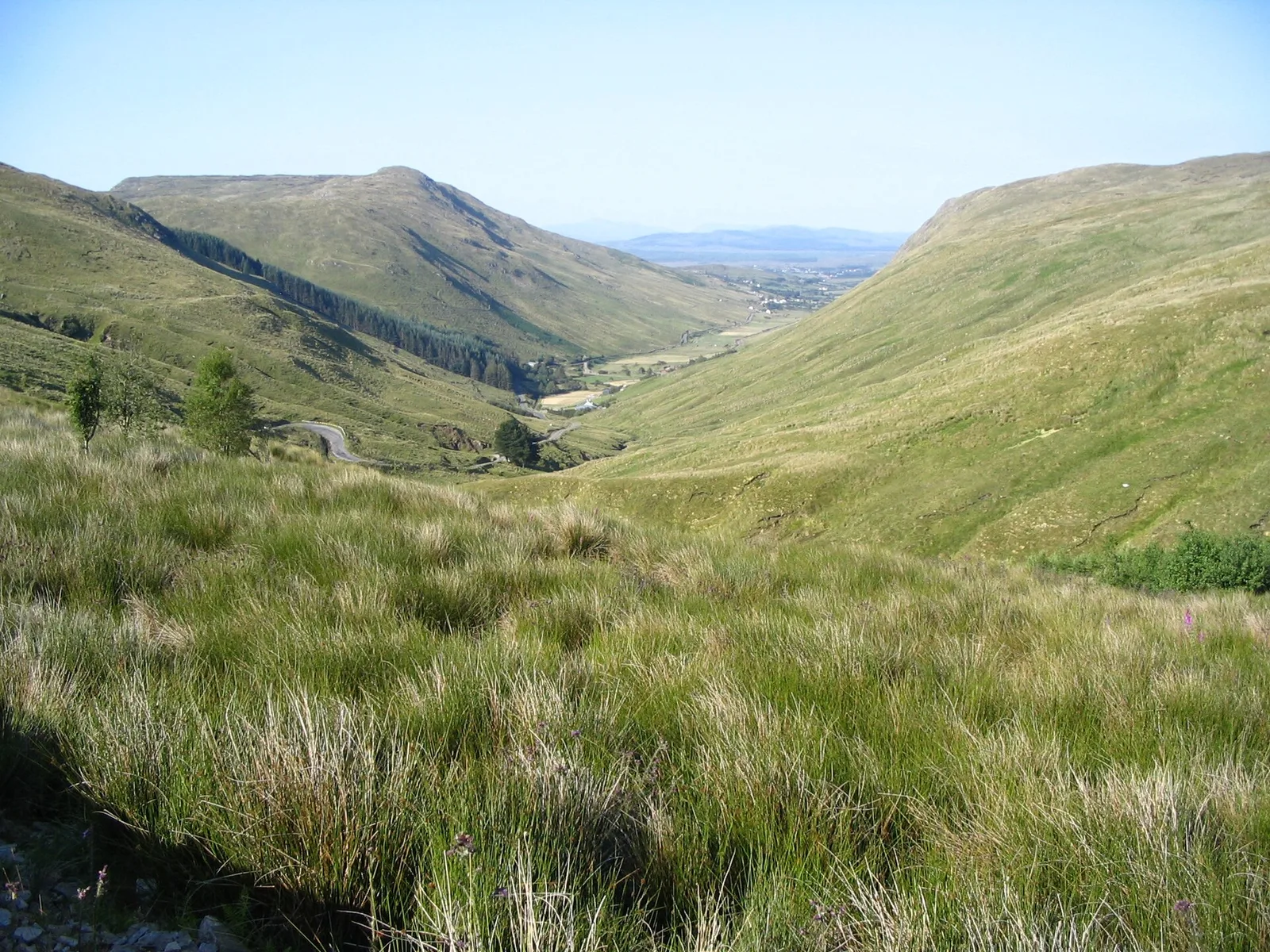 A winding road descends between the green slopes of Glengesh Pass towards Ardara.