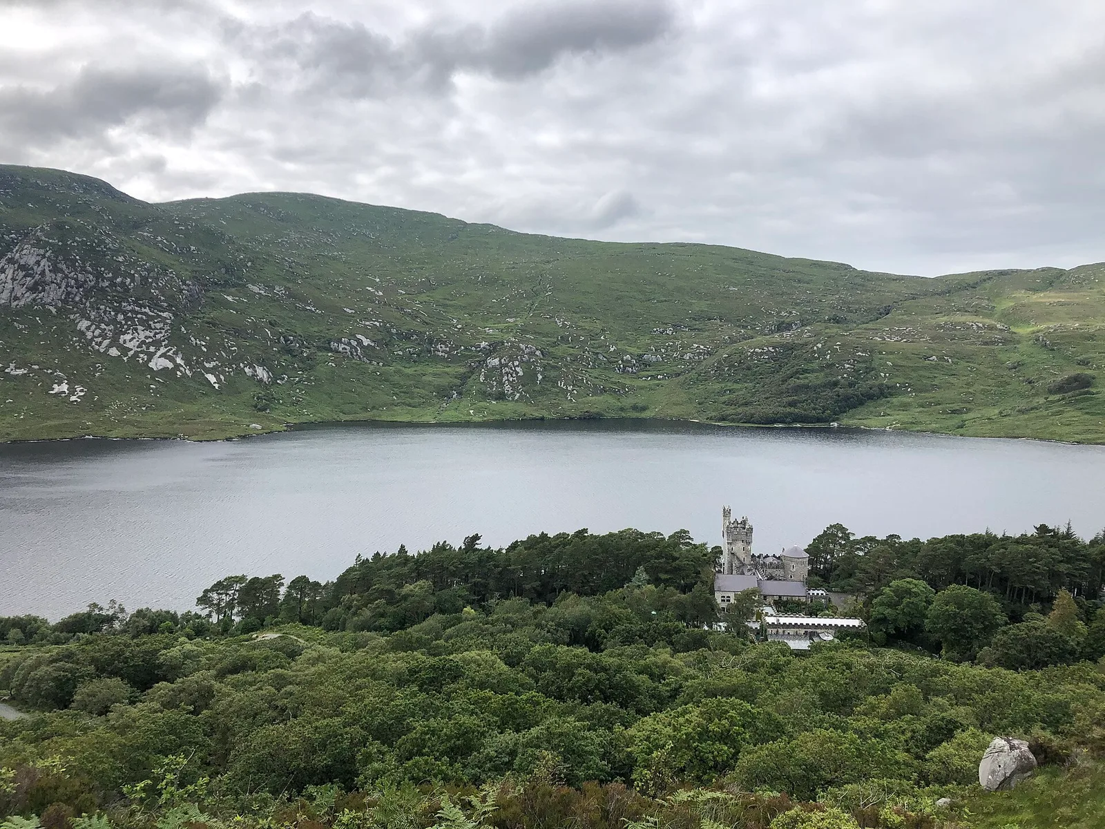 Glenveagh Castle stands among trees beside Lough Beagh and the surrounding hills.