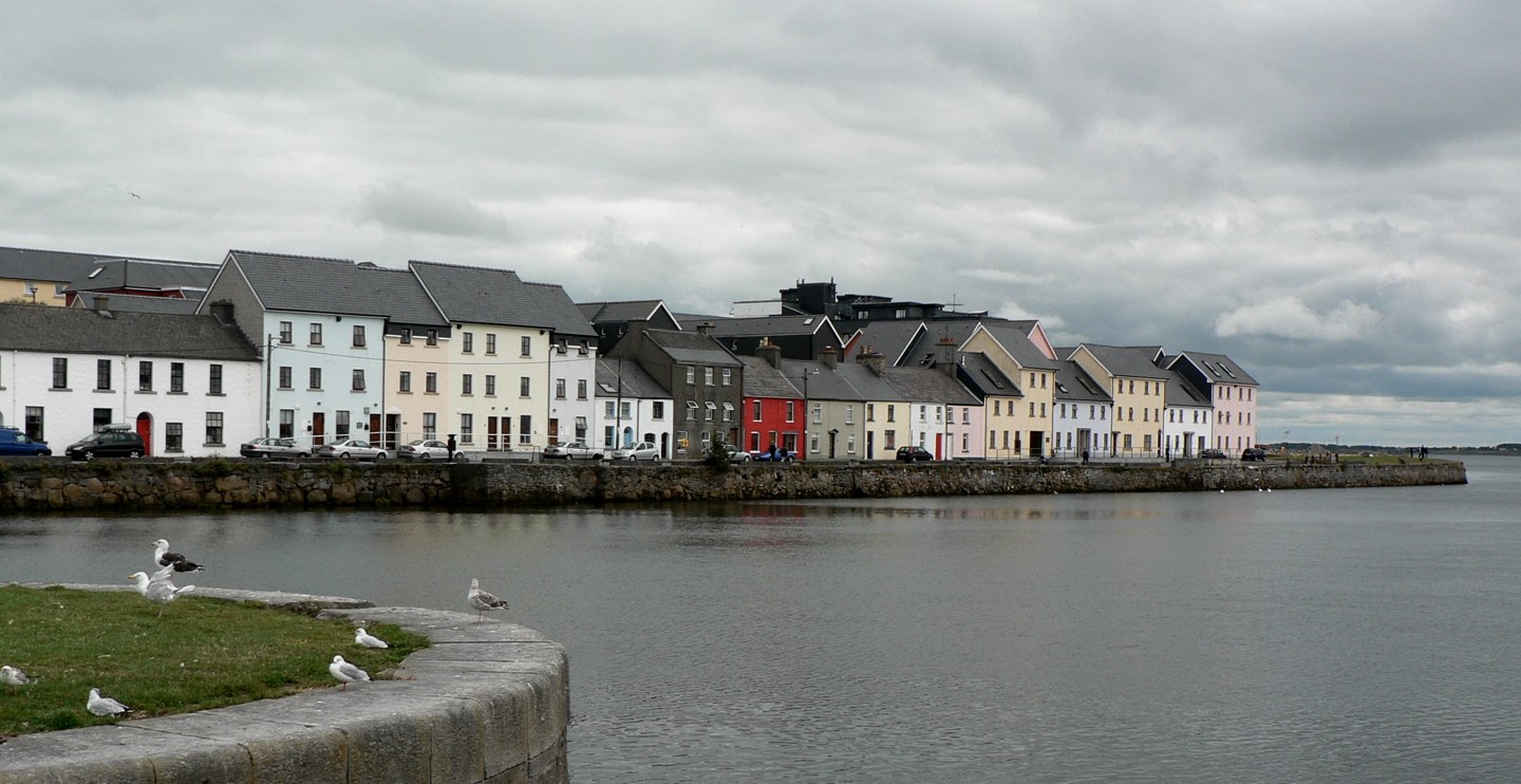 Pastel houses on Galway’s Long Walk beside calm water